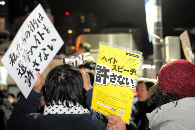 川口駅前であった選挙演説で、「選挙ヘイトを許さない」などと書かれたプラカードを掲げる人たち=2026年1月26日午後7時4分、埼玉県川口市栄町3丁目